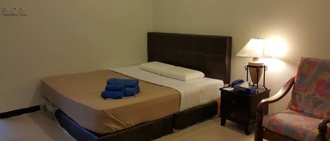 Una habitación de hotel con cama, mesita de noche, lámpara y una silla.