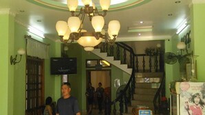 Un vestíbulo de hotel con una escalera, una araña y un televisor en la pared.