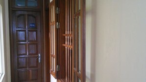 Un pasillo con una puerta de madera marcada con el número "604" y una ventana con contraventanas de madera.