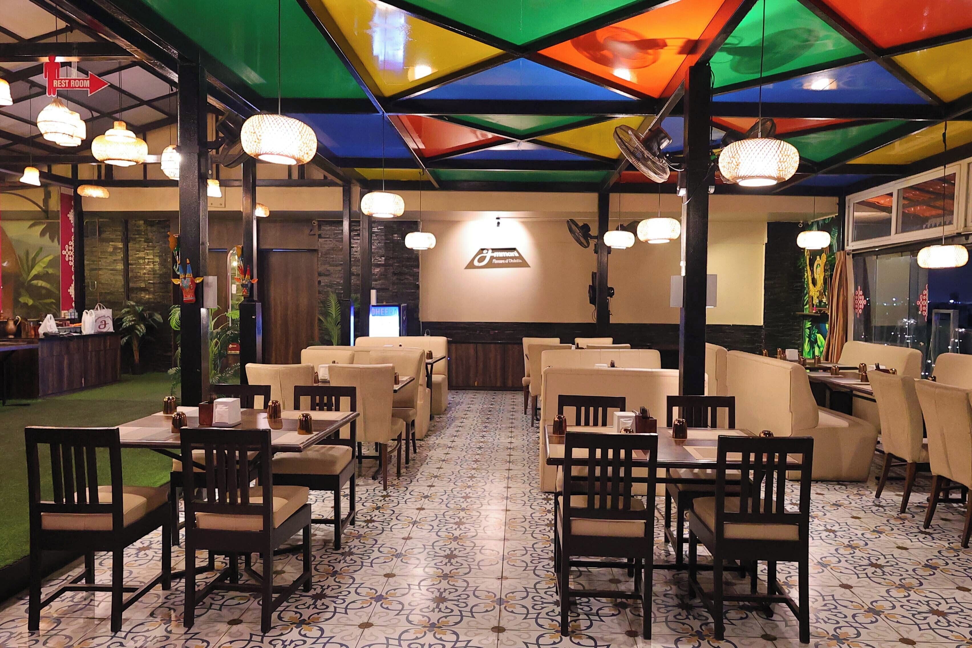 A restaurant with multiple dining areas, including booths and tables, with a patterned floor and a colorful ceiling.