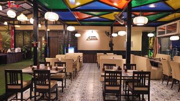 A restaurant with multiple dining areas, including booths and tables, with a patterned floor and a colorful ceiling.