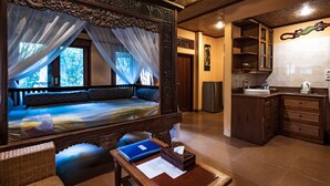 A bedroom with a four-poster bed, a nightstand, and a wooden table with a blue folder and papers. - Murni's Houses and Spa (Ubud)
