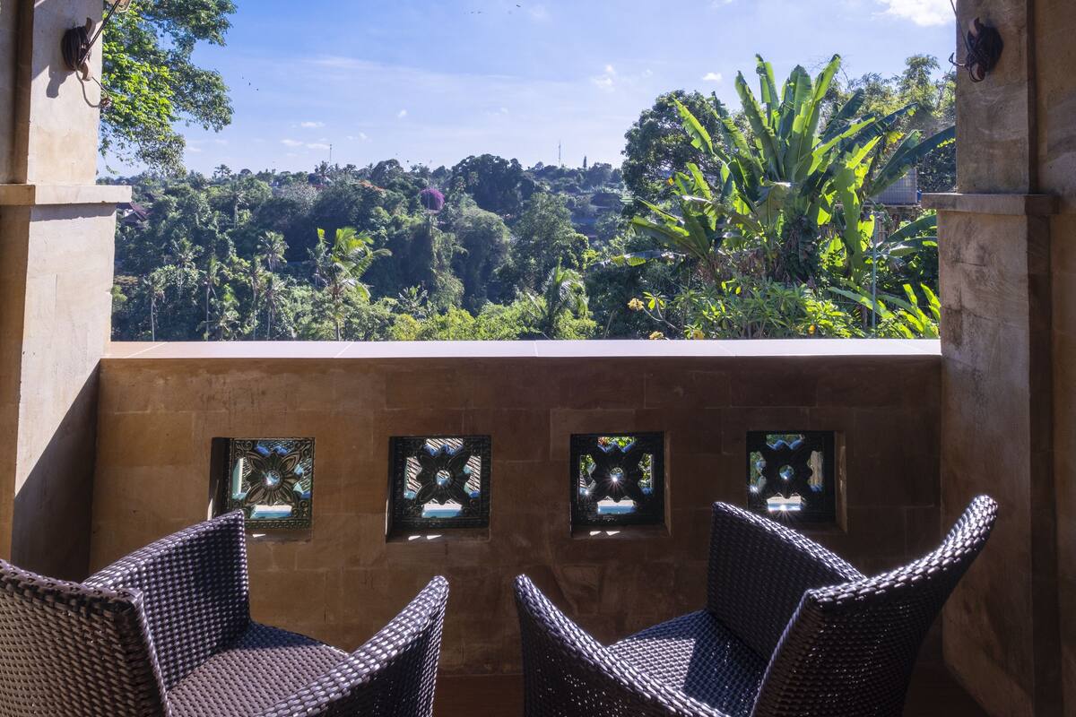 Eine Terrasse mit Korbstühlen und verzierten Fenstern, mit Blick auf einen üppigen Garten.