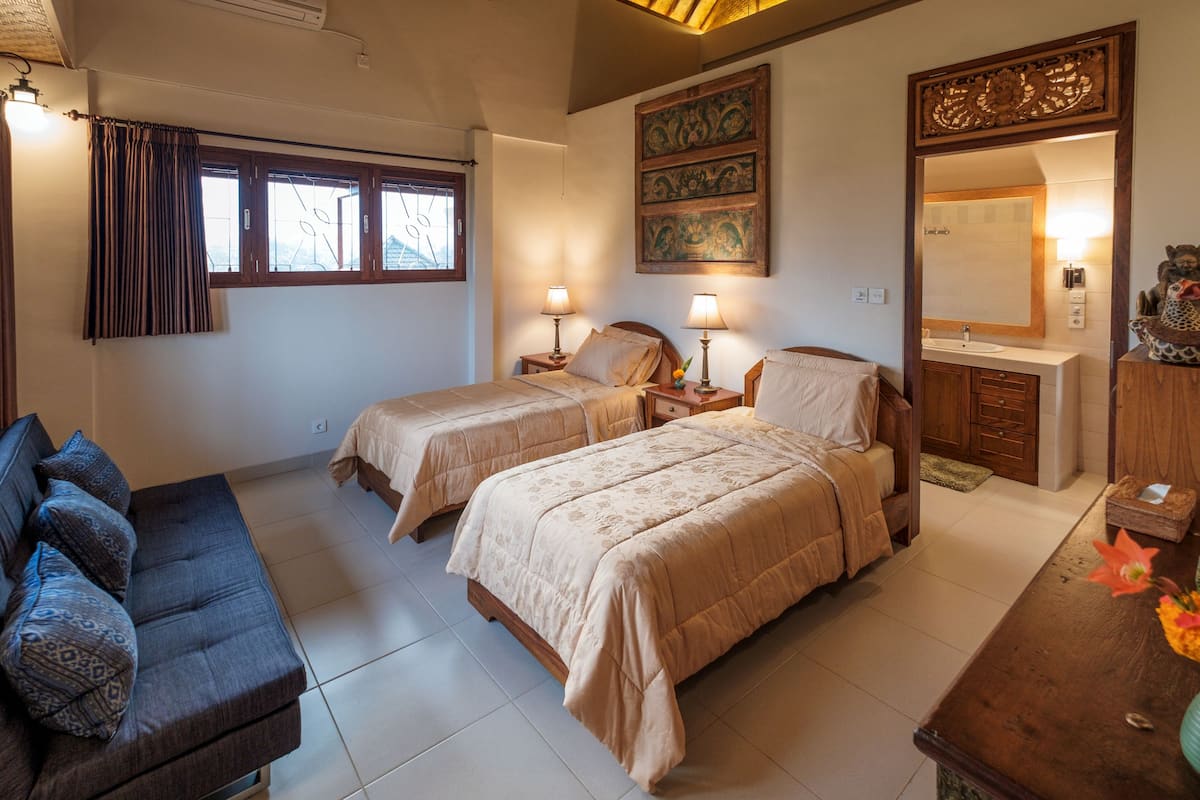 Ein Schlafzimmer mit zwei Betten, einem Schlafsofa, einem Schminktisch mit Spiegel und einer Wanddekoration.