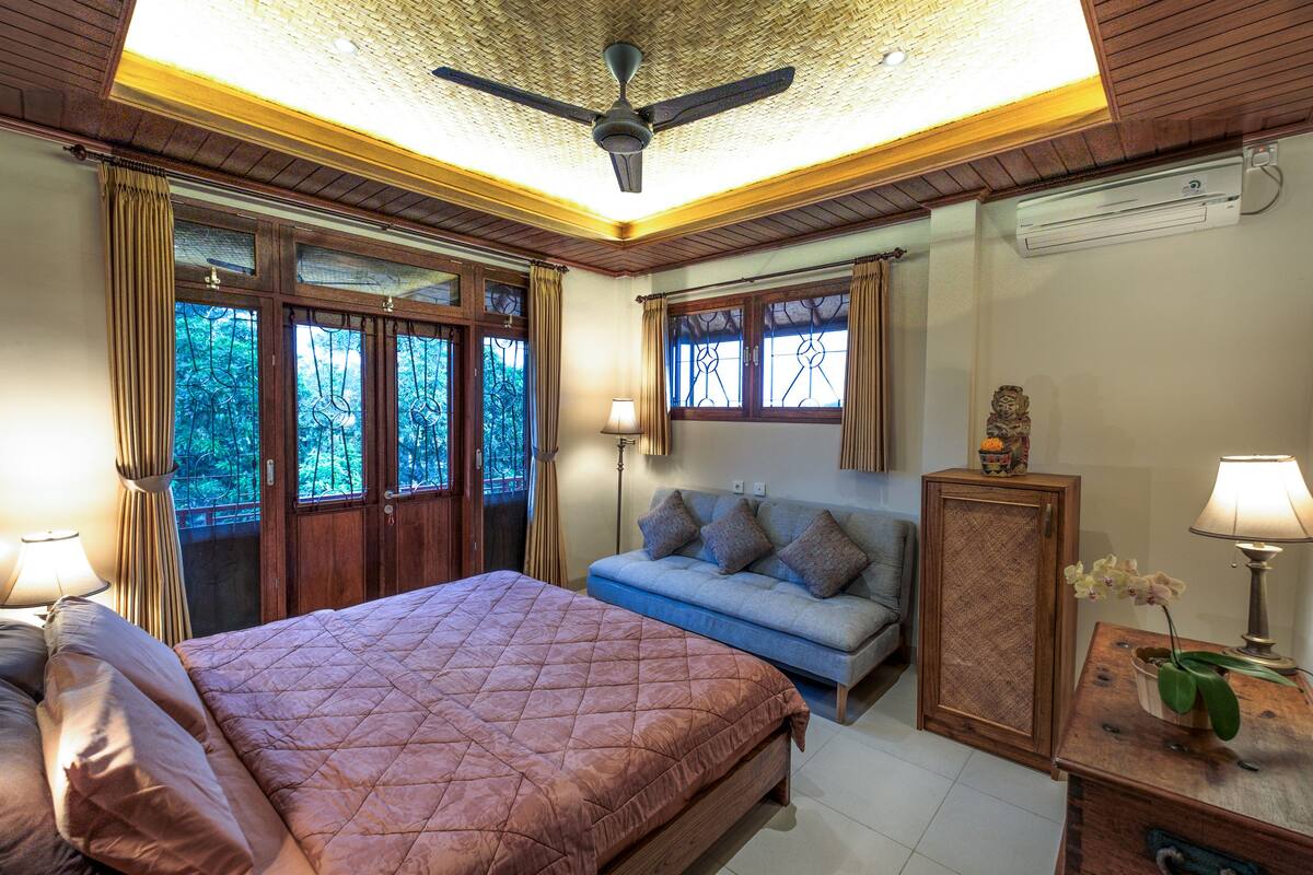 Ein Schlafzimmer mit einem großen Bett, einem Sofa, einem Schrank und einem Deckenventilator.