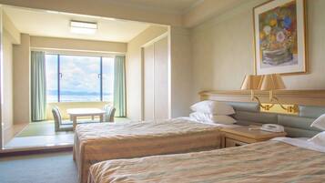 Habitación de hotel con dos camas, un escritorio, una silla y un amplio ventanal con vistas al cielo y las nubes.