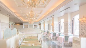 Un comedor elegante con mesas largas, sillas y un escenario central.