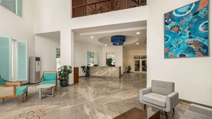 A spacious lobby with a reception desk, seating area, and a large abstract painting. - Ramada by Wyndham Goa Arpora (Arpora)