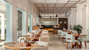 A spacious restaurant with high ceilings, a central bar area, and a checkered floor pattern. - Ramada by Wyndham Goa Arpora (Arpora)