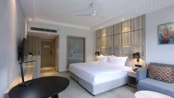 Une chambre d’hôtel moderne avec un grand lit, un canapé, une petite table et un téléviseur.