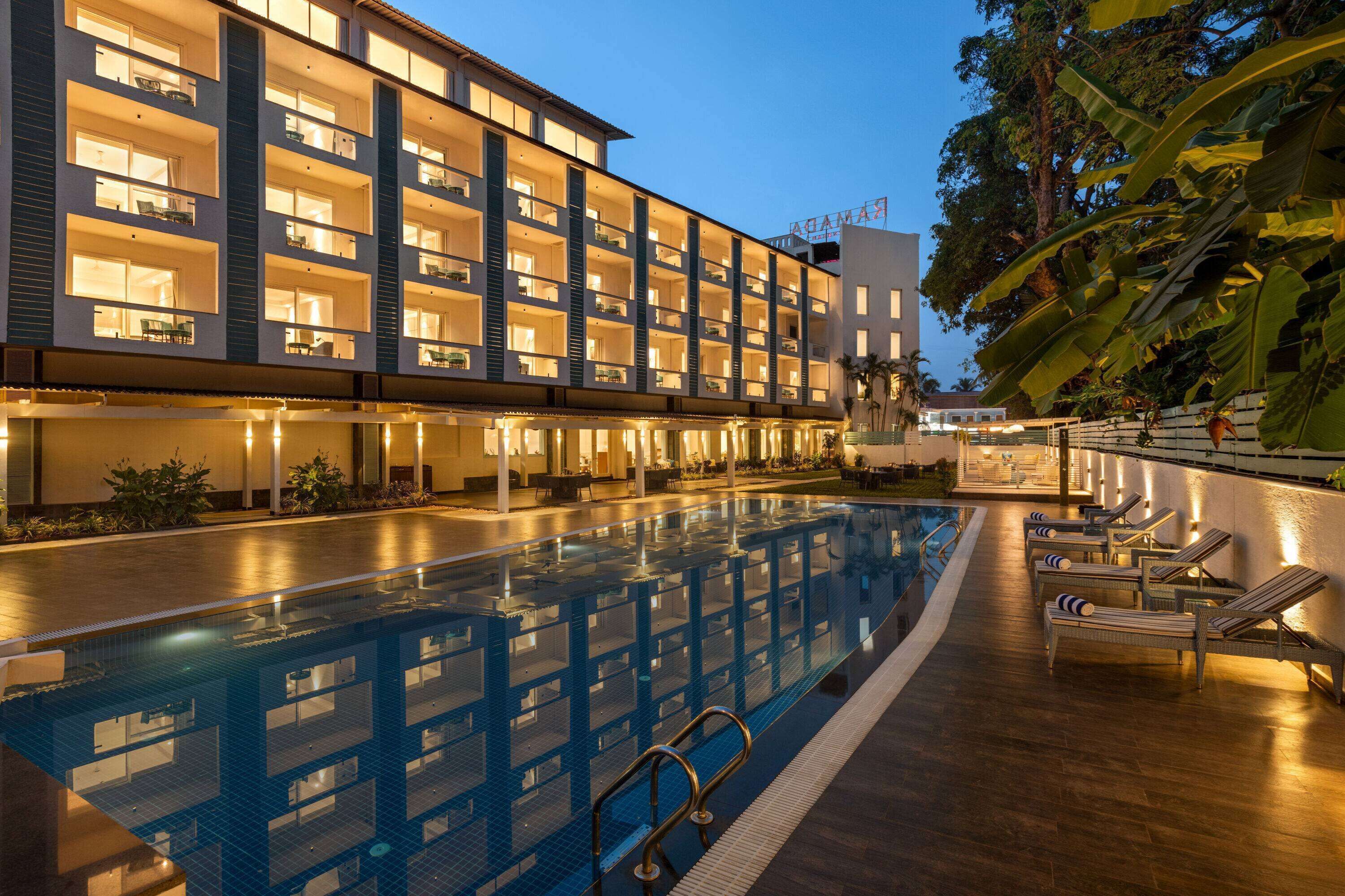 Un hotel con piscina, mobiliario exterior y fachada bien iluminada.