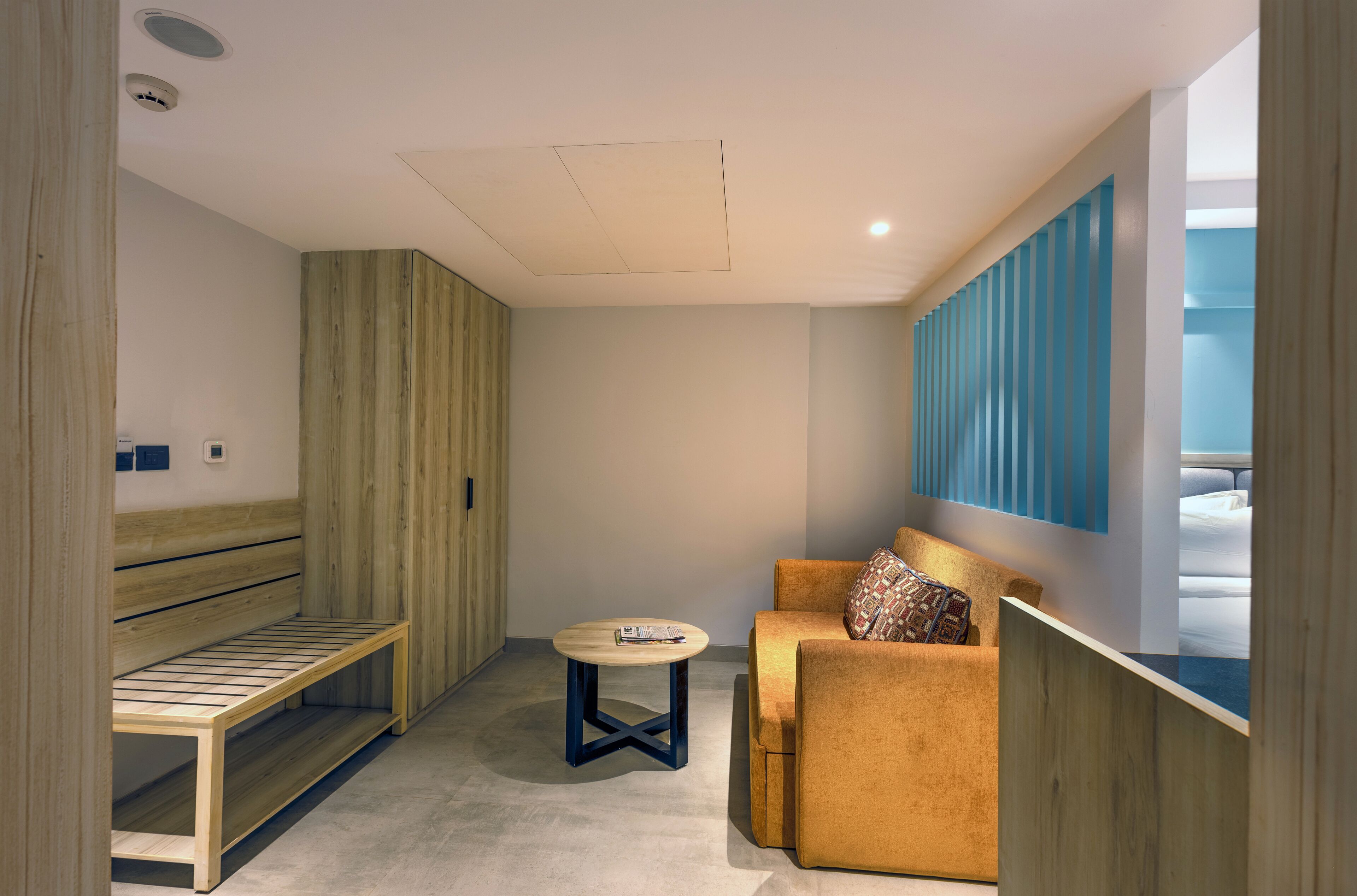 Una habitación moderna con un banco de madera, una mesa redonda y un sofá con un cojín estampado.