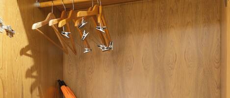 A wooden wardrobe with a folded orange towel, a black radio, and a white pillow.