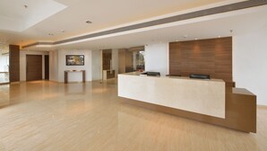 A modern reception area with a central desk, glass partitions, and a polished wooden floor. - Krishna Palace Hotel Ambernath (Ambernath)