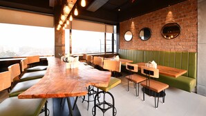 A modern restaurant with a long wooden bar, green cushioned booths, and a brick wall with round mirrors. - Krishna Palace Hotel Ambernath (Ambernath)