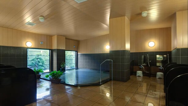 A modern indoor pool area with a glass-enclosed hot tub, tiled walls, and a wooden ceiling.