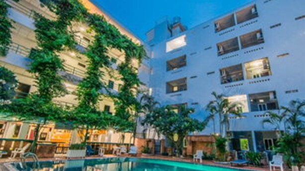 A hotel with a swimming pool, outdoor seating, and greenery. - Sutus Court 2 (Pattaya)