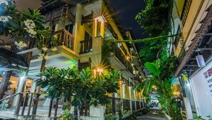 A multi-story hotel with balconies, lush greenery, and a well-lit entrance. - Sutus Court 2 (Pattaya)