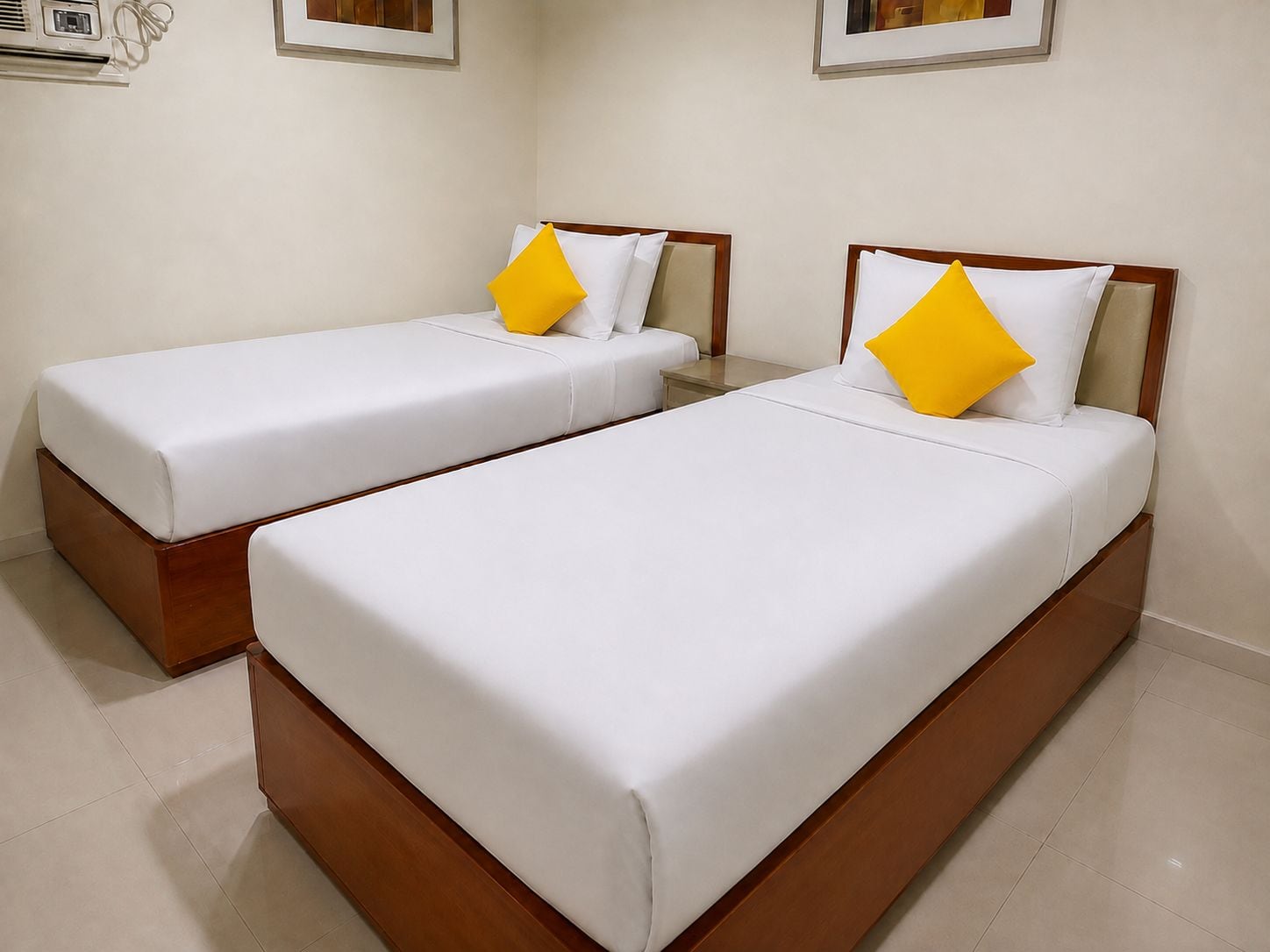 Two single beds with wooden frames and white bedding, each with a yellow pillow.