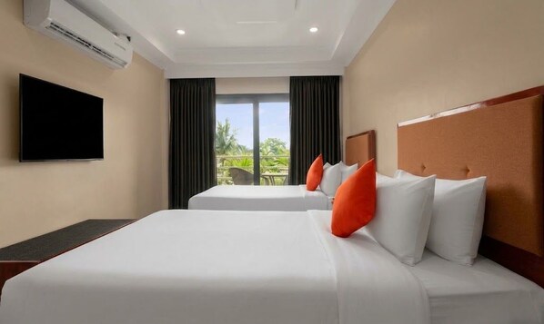 Habitación de hotel con dos camas, un televisor de pantalla plana y vistas al exterior.