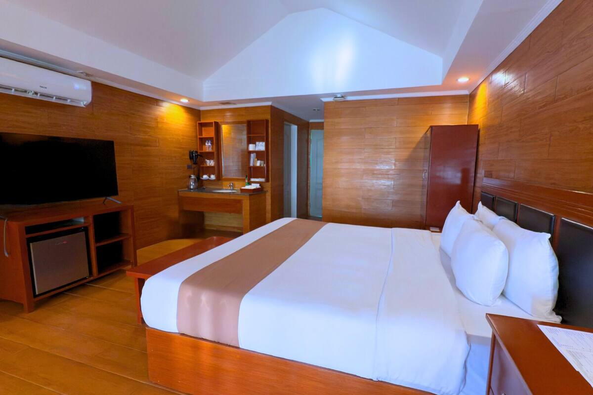 A hotel room with a large bed, a TV, a desk, and a bathroom.