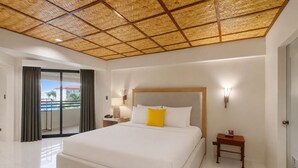 A hotel room with a large bed, a nightstand, a lamp, and a view of the outdoors. - Whiterock Beach Resort (Subic)