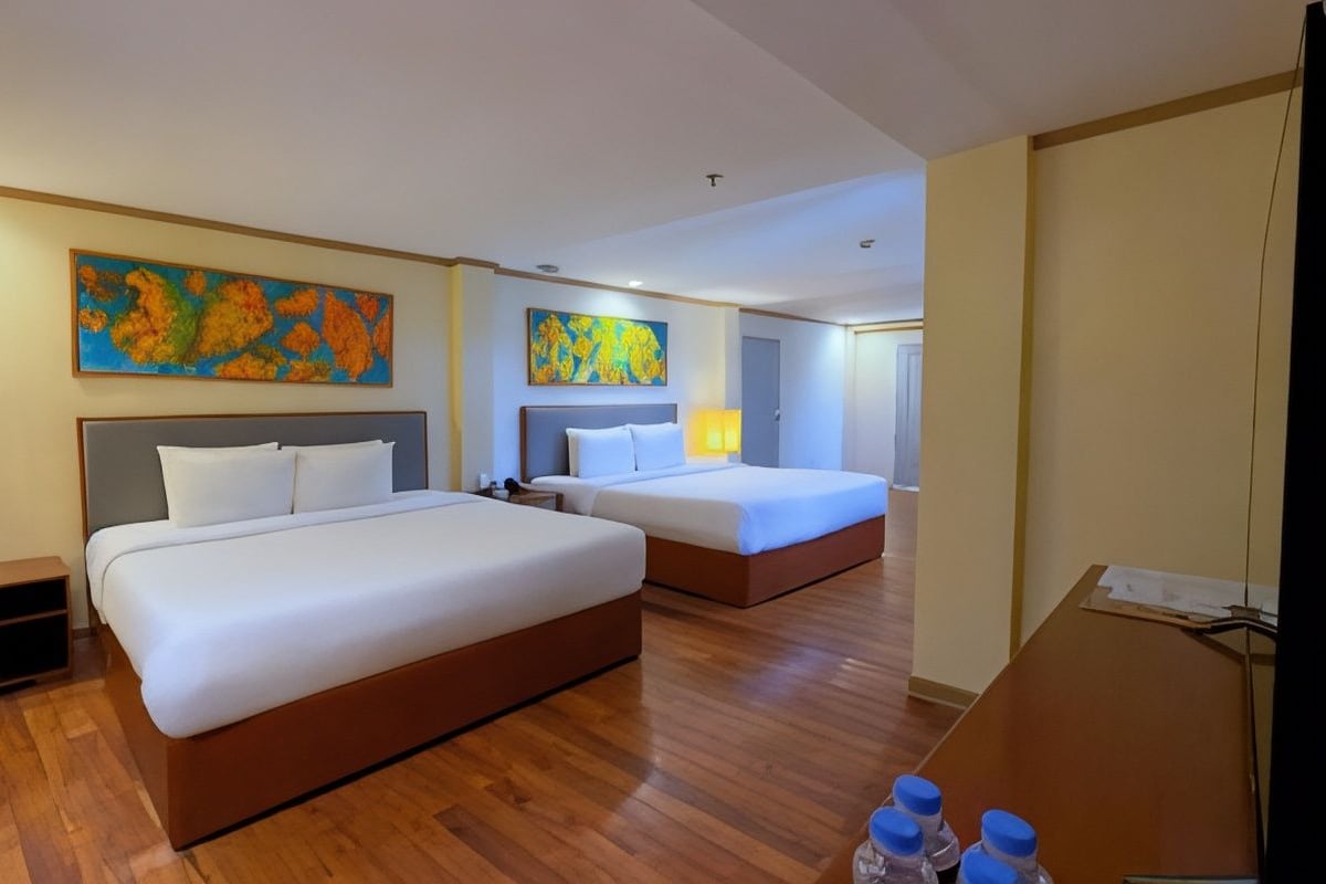 Habitación de hotel con dos camas, suelo de madera y obras de arte en las paredes.