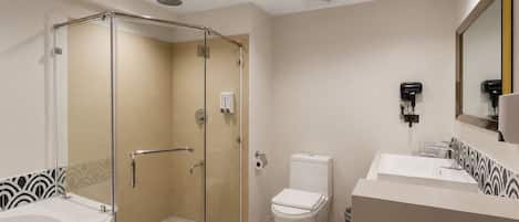 A modern bathroom with a glass-enclosed shower, a toilet, and a sink with a mirror.