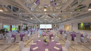 A conference room with round tables, white chairs, and a large screen at the front. - Whiterock Beach Resort (Subic)