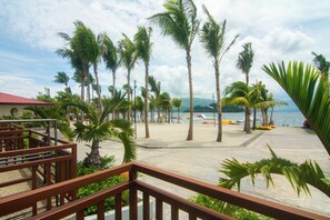 A beachside view with palm trees, a sandy area, and a body of water. - Whiterock Beach Resort (Subic)
