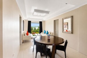 A modern hotel room with a dining area, a large window with a view, and a framed picture on the wall. - Whiterock Beach Resort (Subic)