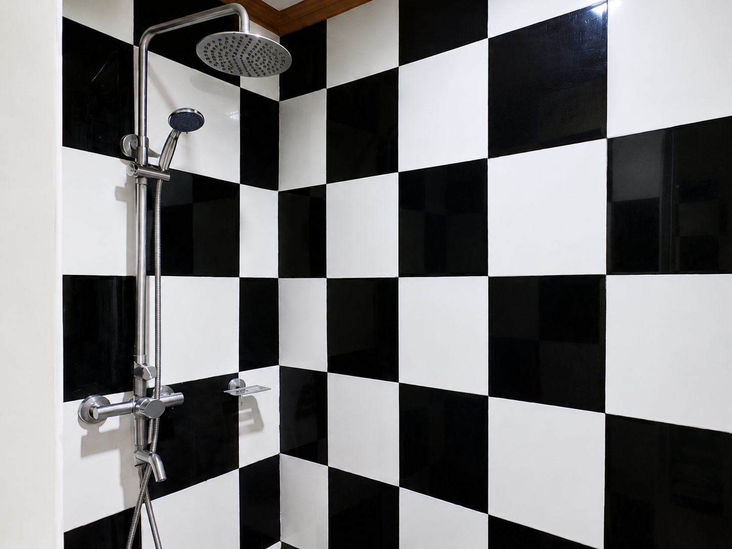 A bathroom with a black and white checkered tile pattern, a chrome showerhead, and a handheld shower attachment.