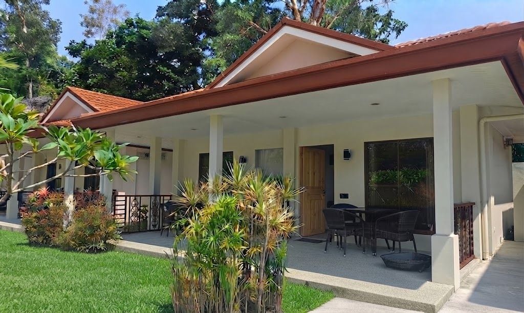 A covered outdoor area with a patio, seating, and a view of the surrounding greenery.
