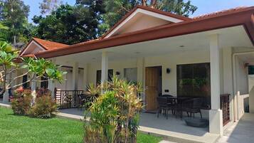 A covered outdoor area with a patio, seating, and a view of the surrounding greenery.