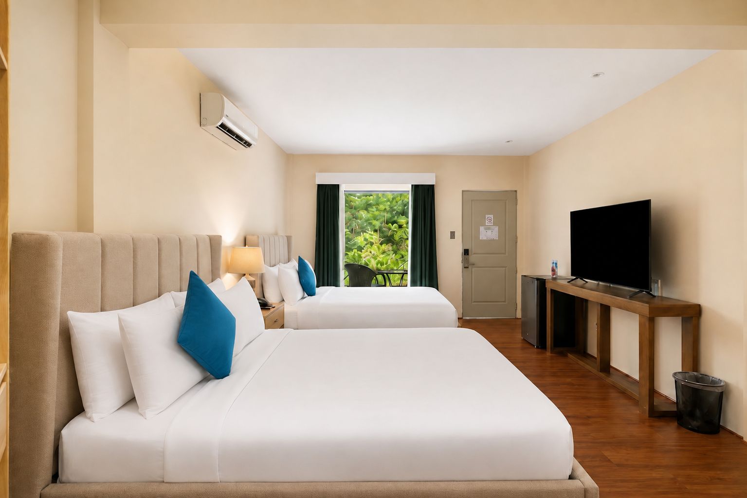 Une chambre d’hôtel avec deux lits, une télévision, un bureau et une vue sur la verdure environnante.