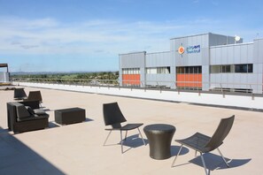 Eine Dachterrasse mit Sitzgelegenheiten und Blick auf das Flughafengebäude.