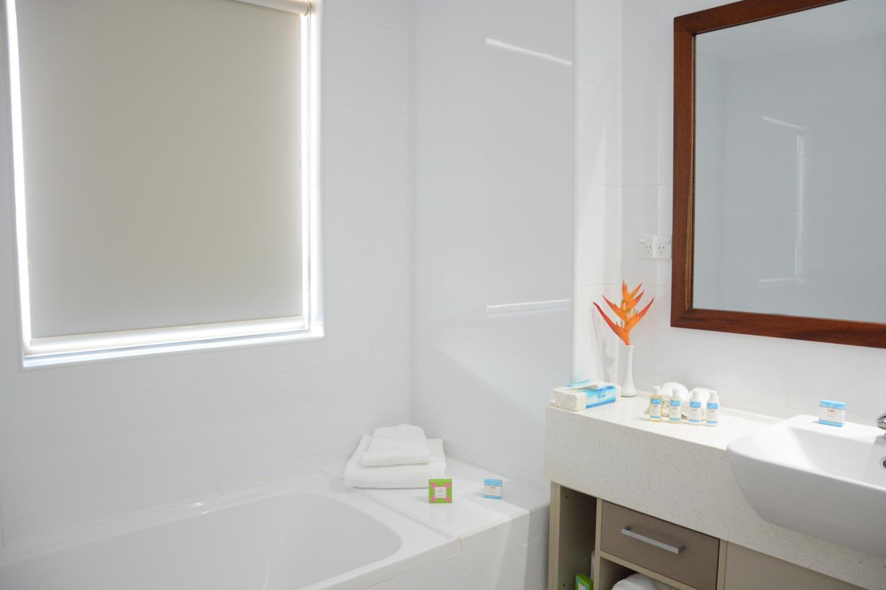 A modern bathroom with a bathtub, a sink, and a large mirror.