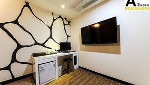 Habitación de hotel moderna con escritorio blanco, televisor de pantalla plana montado en la pared y un diseño único en blanco y negro.
