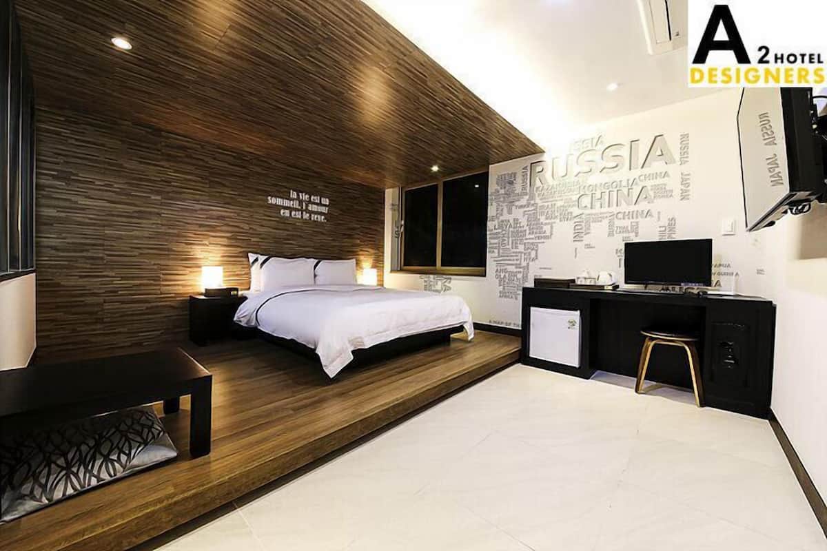 Una habitación de hotel moderna con un muro decorativo de madera, una cama, mesitas de noche, un escritorio y un televisor.