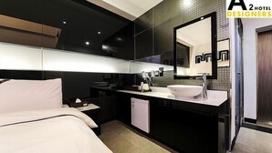 Una habitación de hotel moderna con una cama grande, un baño en blanco y negro, y un espejo amplio.