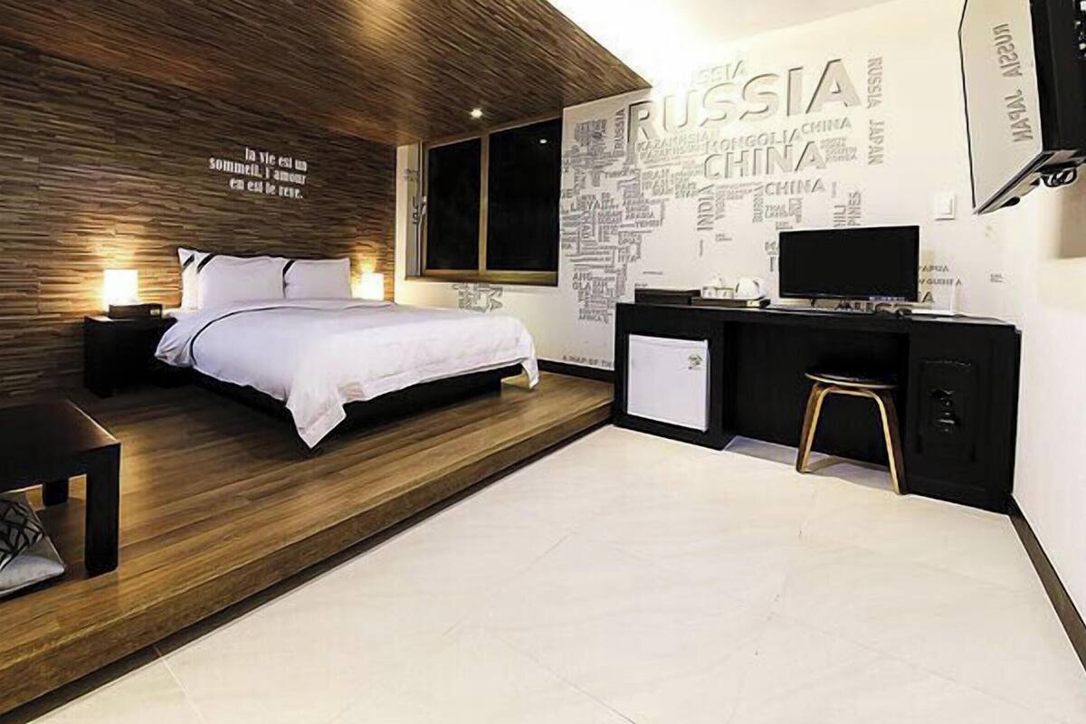 Un dormitorio moderno con cama, mesita de noche y un escritorio con silla.