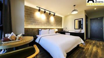 A hotel room with a bed, bedside table, and a small dining table with breakfast items.