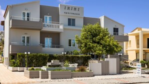 A multi-story building labeled "IRINI apartments" with balconies, outdoor seating, and a landscaped garden area. - Irini Stalos Apartments (Chania)