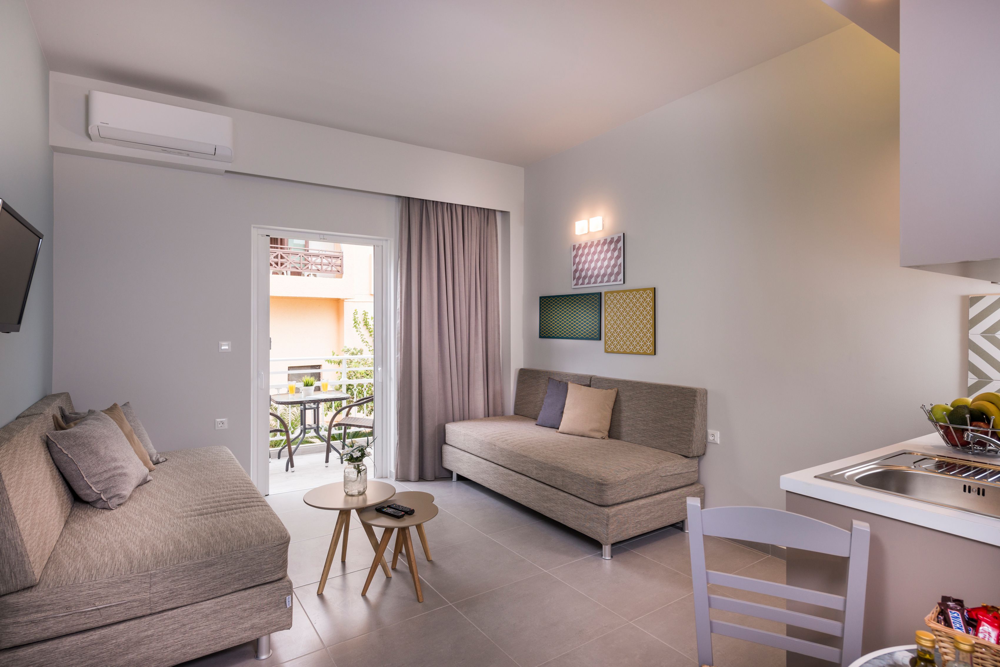 Una sala de estar moderna con un sofá, una mesa de comedor y una zona de cocina con un lavamanos.