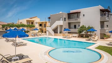 Relax by the central pool surrounded by lounge chairs and umbrellas.