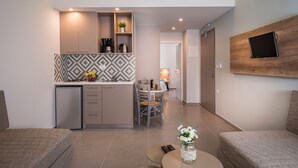 A modern kitchen with built-in appliances, a dining area with a table and chairs, and a living area with a sofa and a coffee table. - Irini Stalos Apartments (Chania)