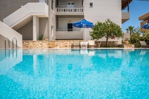 Una piscina al aire libre, sombrillas, sillones reclinables de piscina