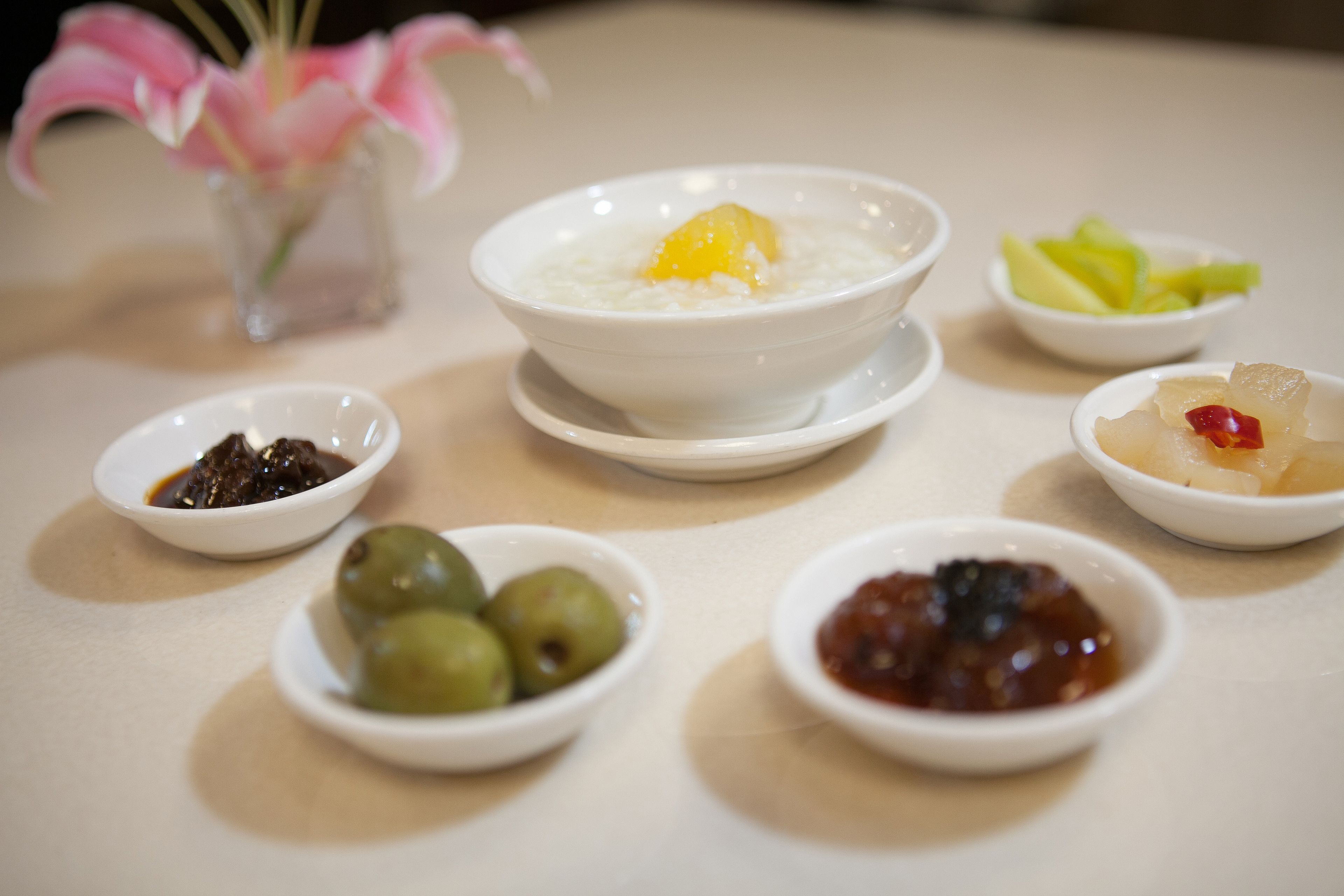 A table with various dishes including a bowl of rice, a bowl of fruit, and several small bowls of condiments.