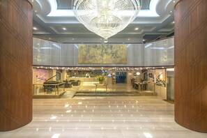 A spacious lobby with a grand chandelier, a reception desk, and a piano. - Chiayi King Hotel (Chiayi City)
