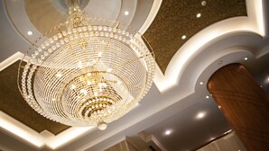 Um candelabro com várias camadas de cristais e luzes, um pilar de madeira e um teto trabalhado.